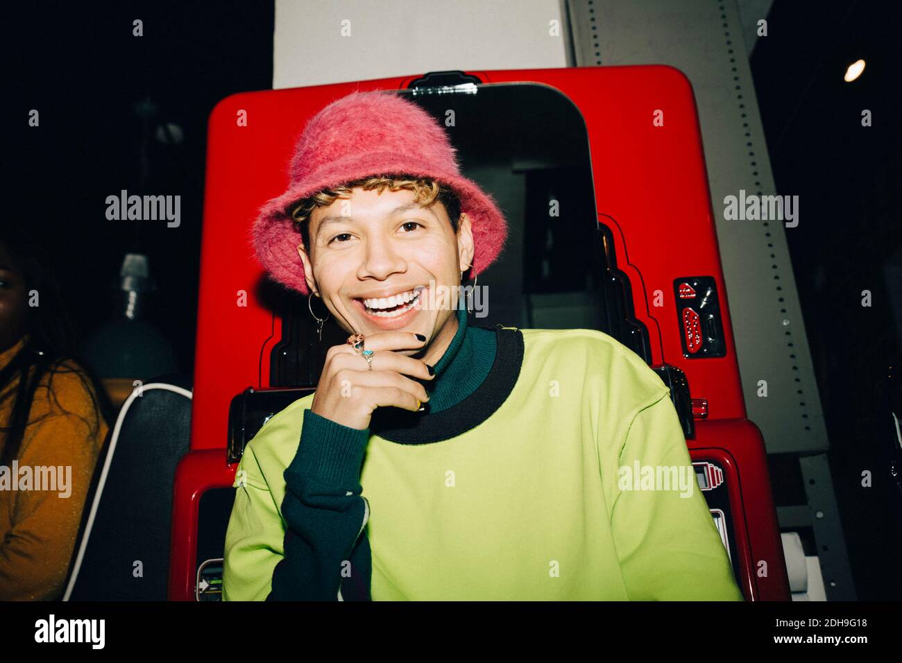 Portrait of smiling man wearing hat standing against vending machine in cafe Stock Photo
