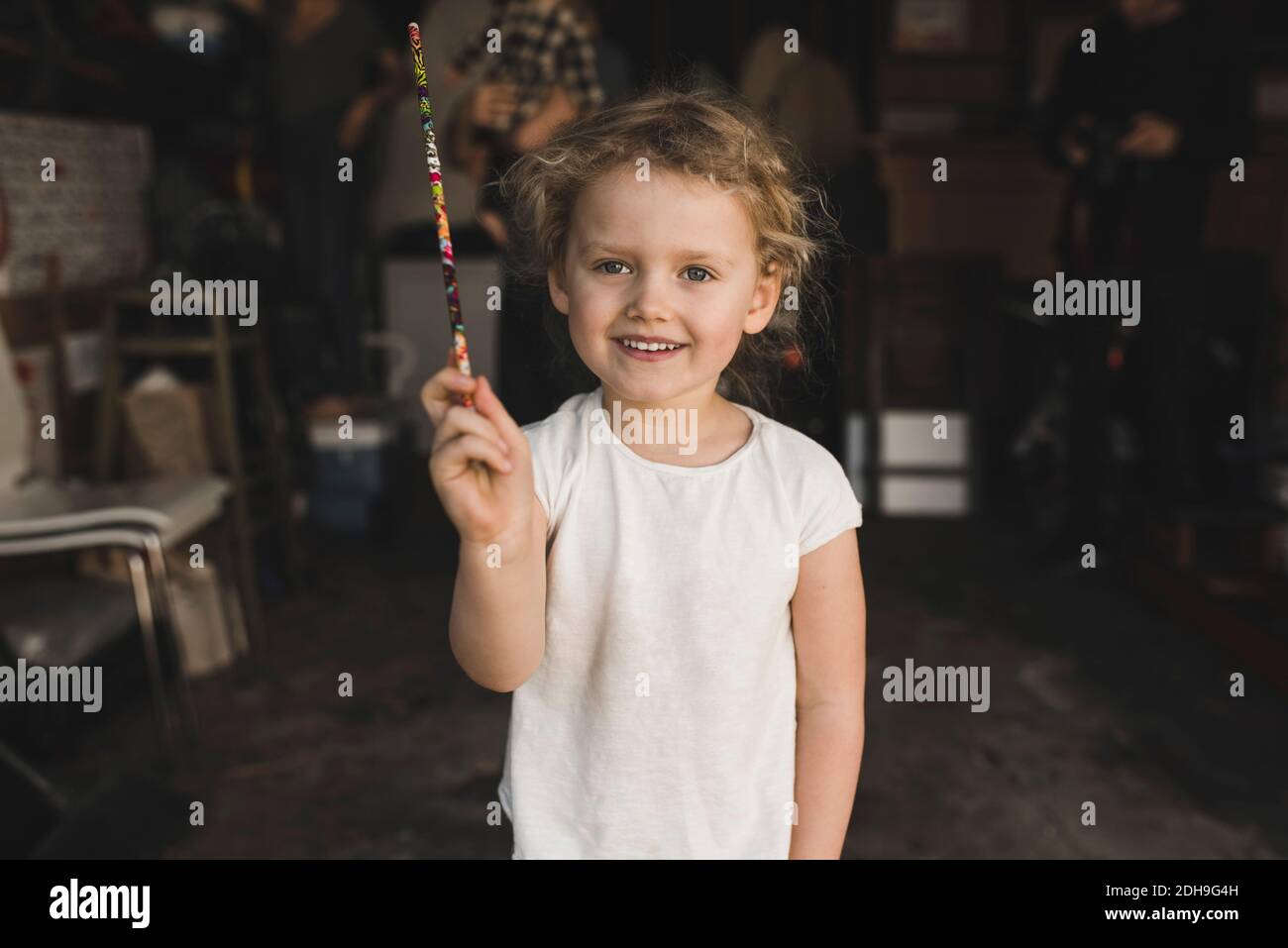 Portrait of girl showing magic wand in storage room Stock Photo