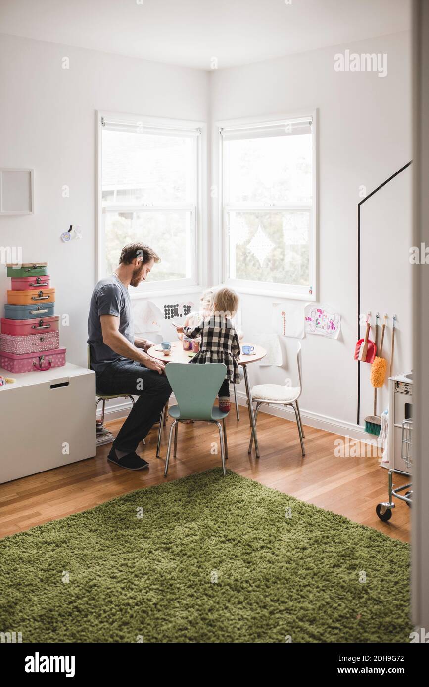 Father playing with daughter at small dining table in playroom Stock Photo