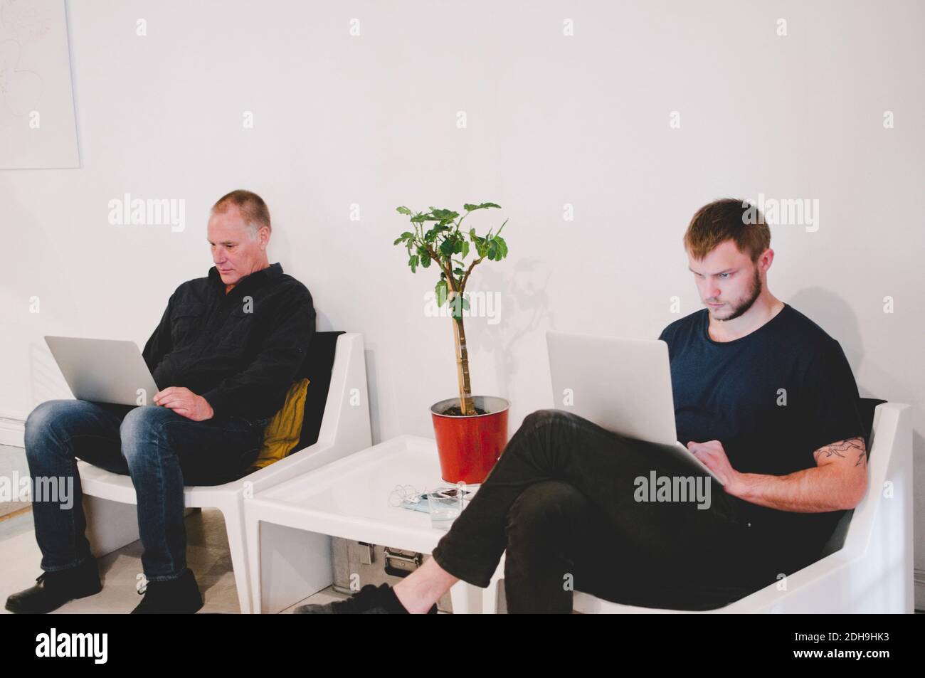 Businessmen using laptops while sitting at lobby in creative office Stock Photo