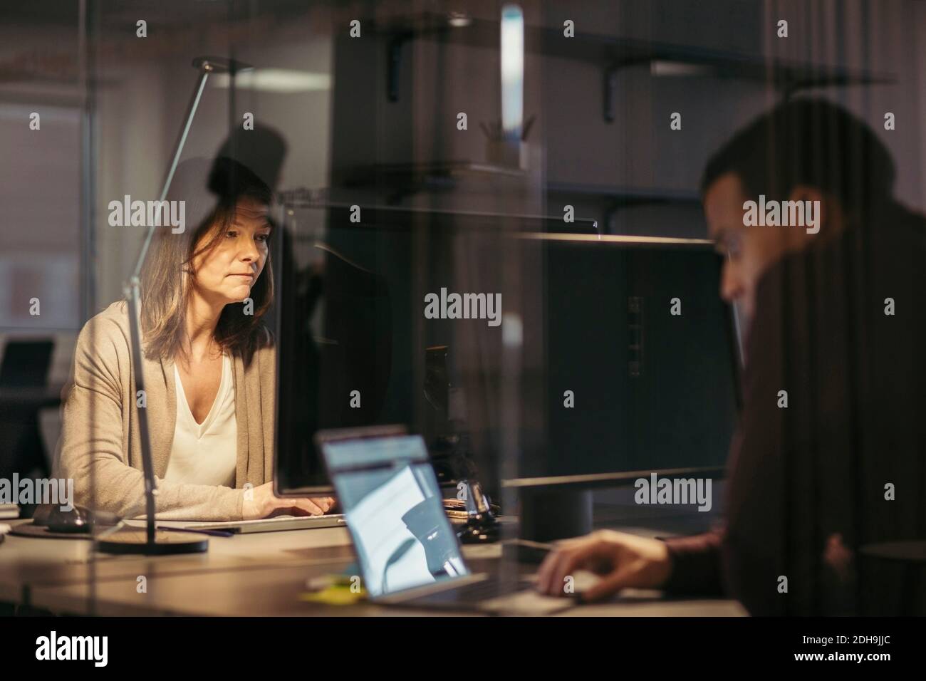 Business colleagues using technology while working late at office Stock Photo