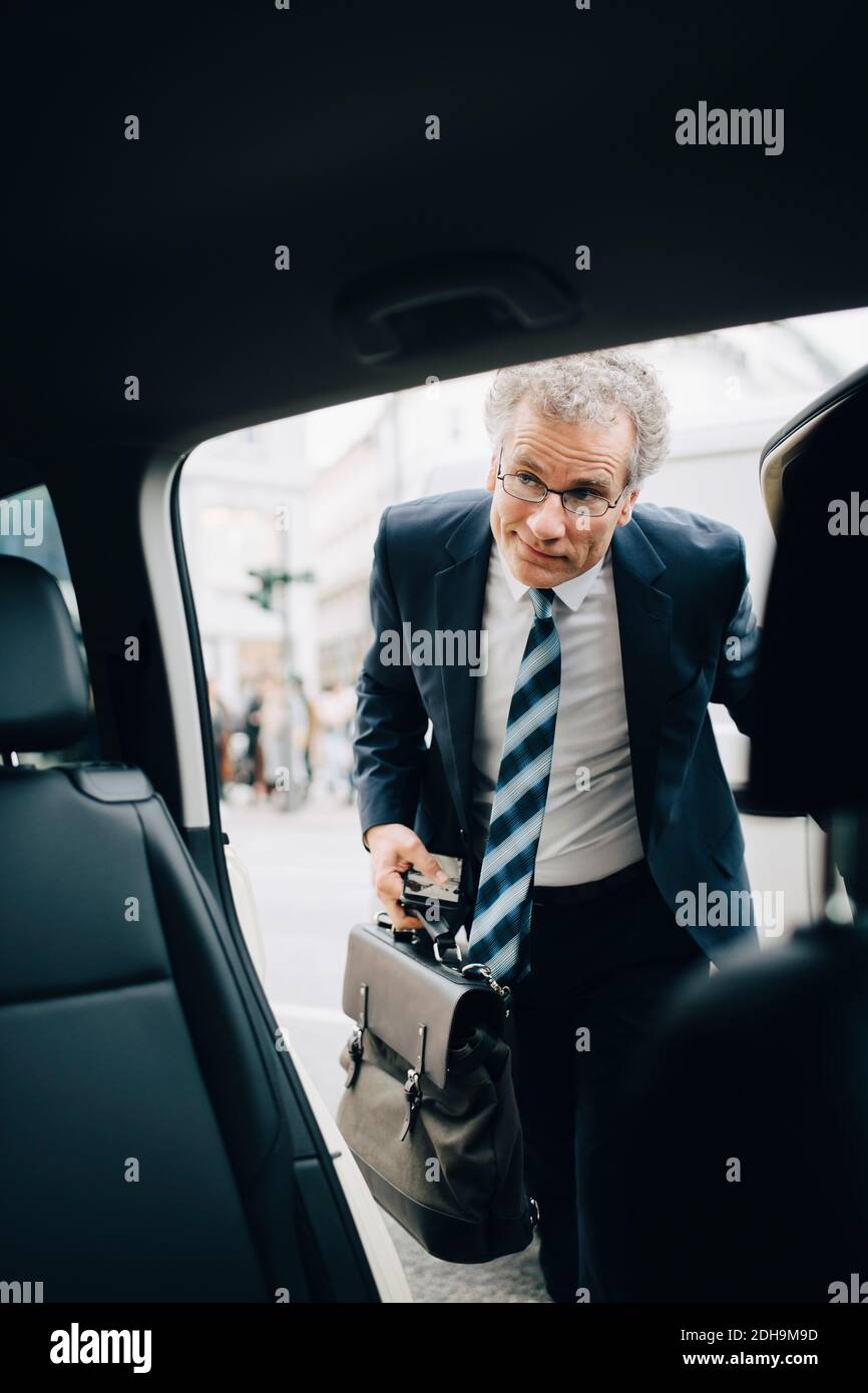 Mature male entrepreneur getting in taxi during business trip Stock Photo