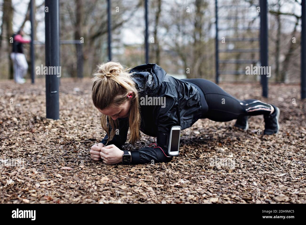 Full length of female athlete performing plank position in forest Stock Photo