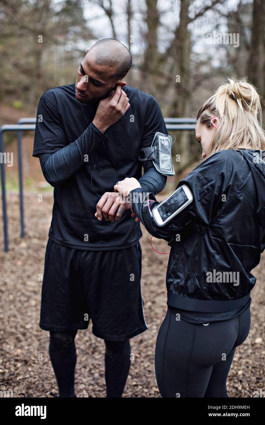 Male and female athletes wearing technologies in forest Stock Photo