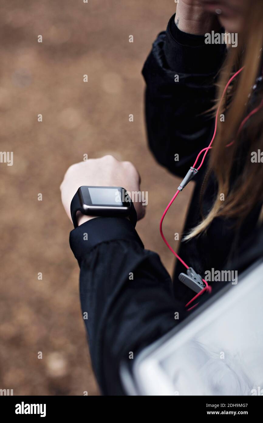 Cropped image of female athlete checking fitness tracker in forest Stock Photo