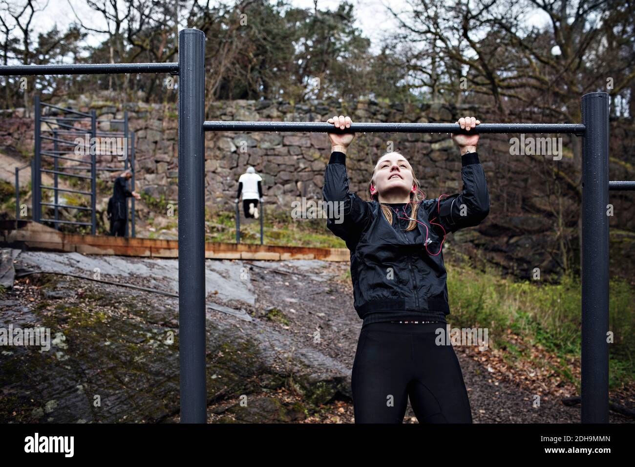 Young woman doing chin-ups exercise at outdoor gym Stock Photo