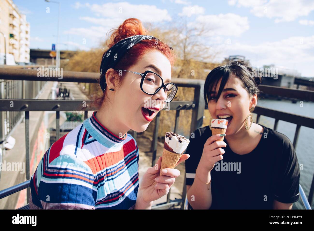 Portrait of hipster female friends eating ice cream in city Stock Photo