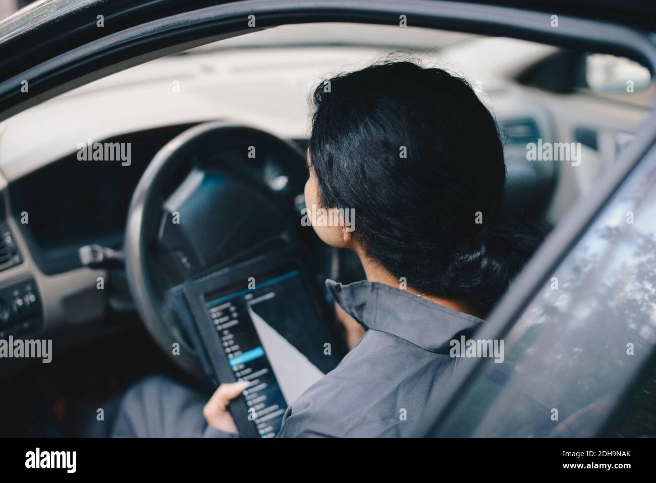 Female mechanic using digital tablet while sitting in car Stock Photo