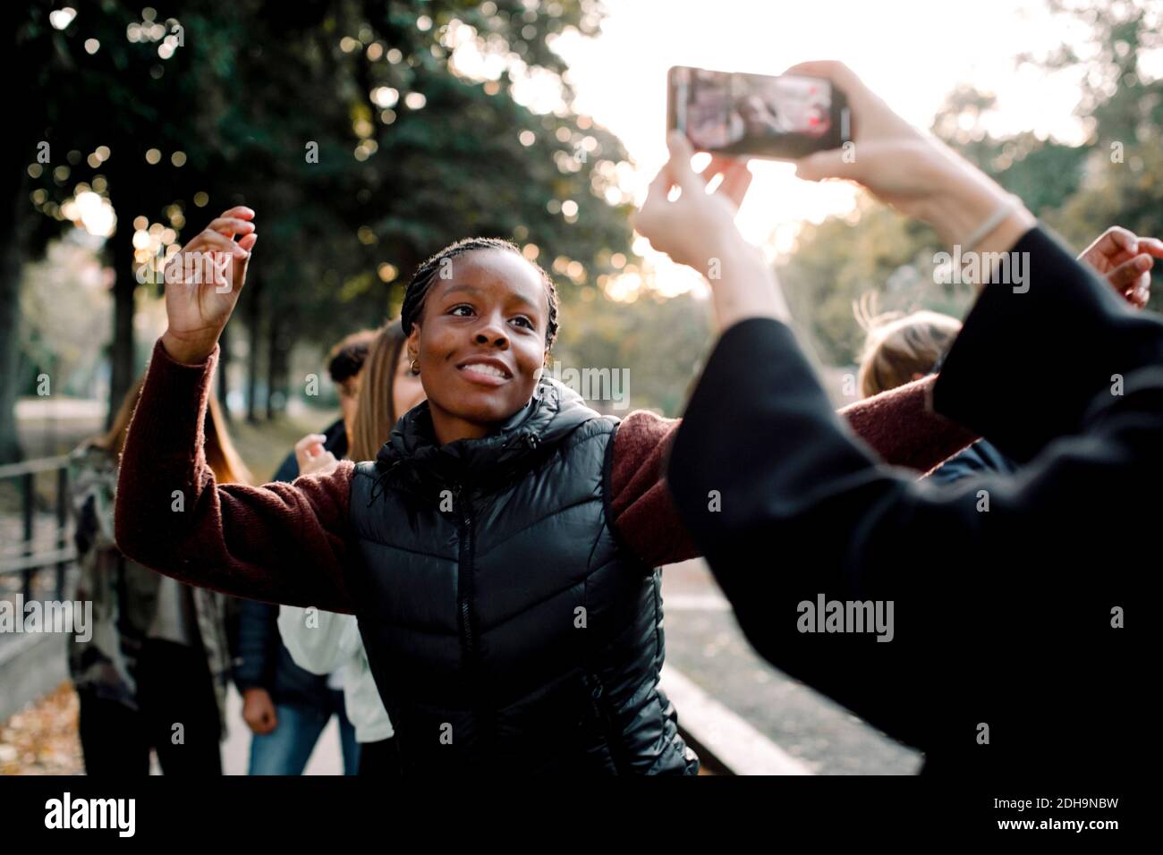 Cropped hands of woman filming teenage girl dancing on street in city Stock Photo