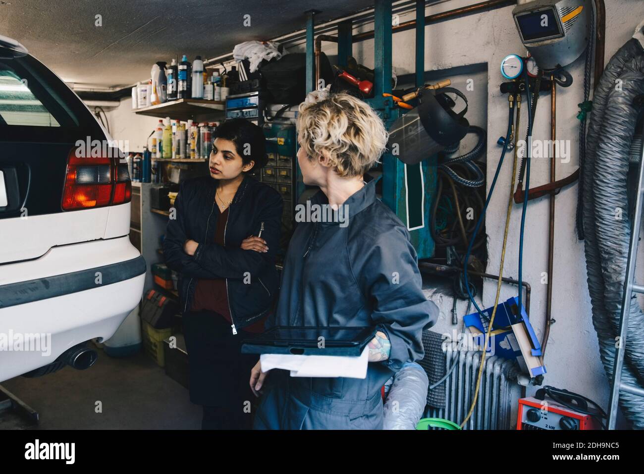 Female mechanic with customer examining car at auto repair shop Stock ...