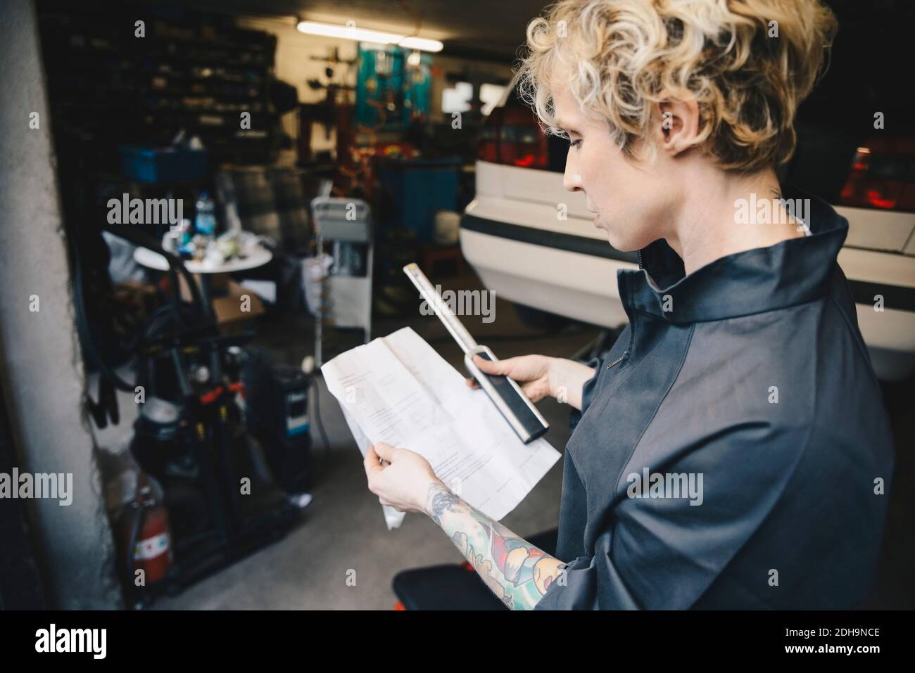 Side view of female mechanic reading checklist at auto repair shop Stock Photo