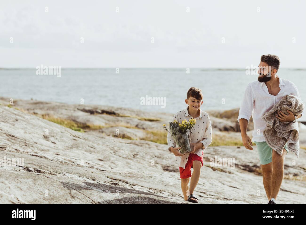 Smiling father holding blanket while bonding with son during summer Stock Photo