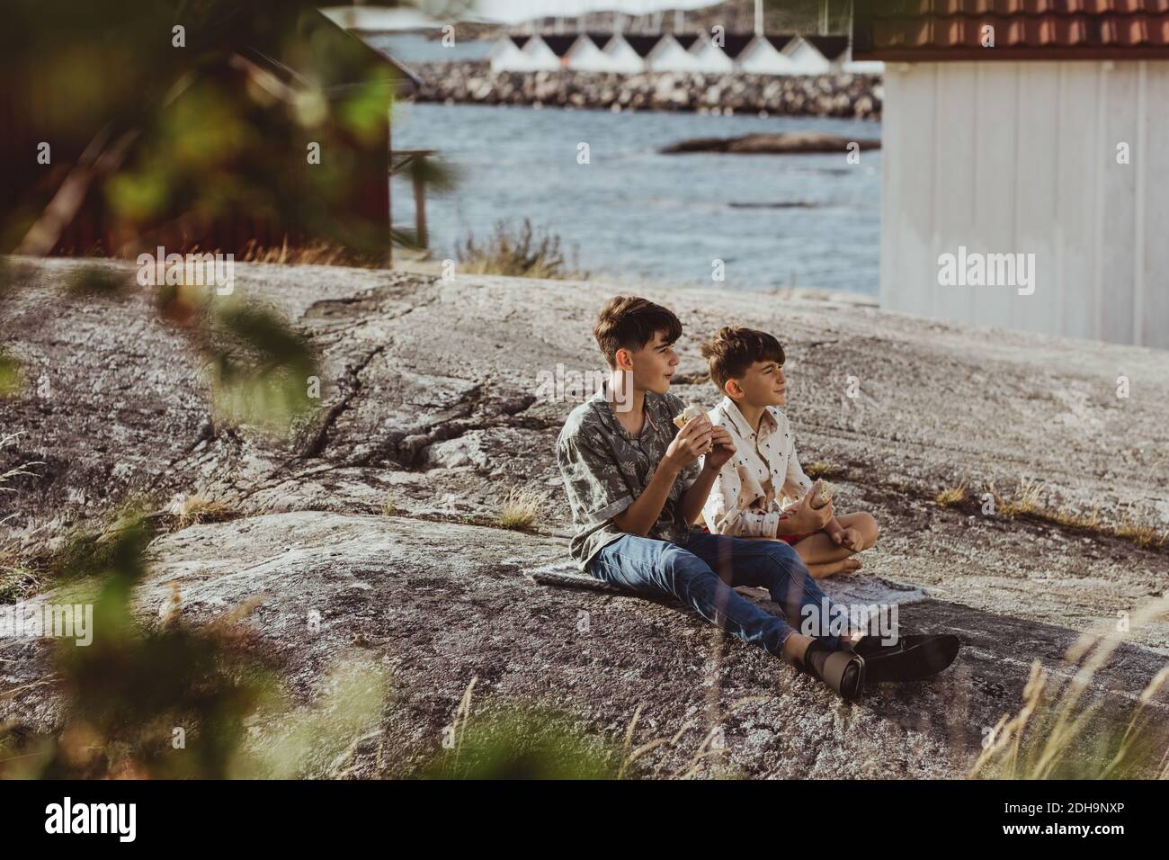 Male siblings looking away while sitting on blanket over archipelago during weekend Stock Photo