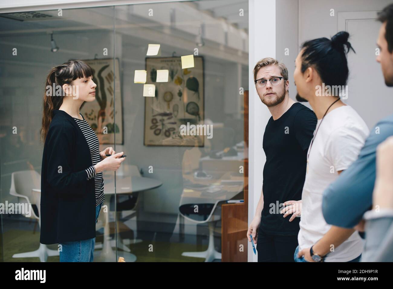 Male and female programmers discussing over adhesive notes stuck on ...