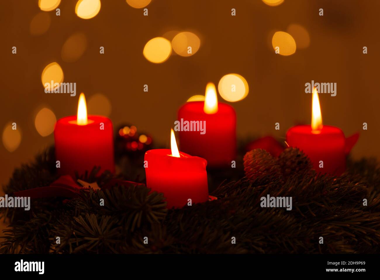 Four burning red Advent candles on Christmas Eve with bokeh lights on