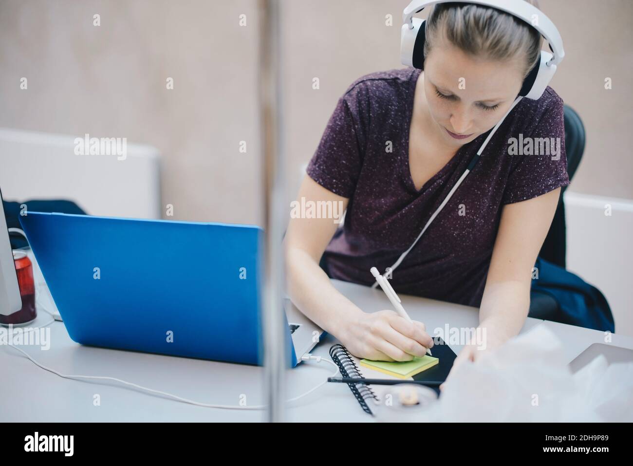 Female computer programmer writing on adhesive note while working in office Stock Photo