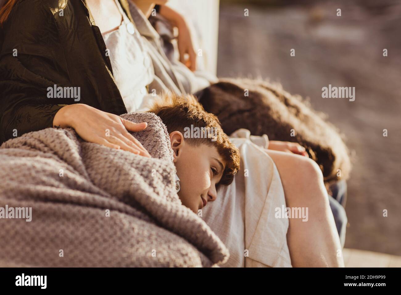 Tired son sleeping on mother's lap during summer Stock Photo Alamy