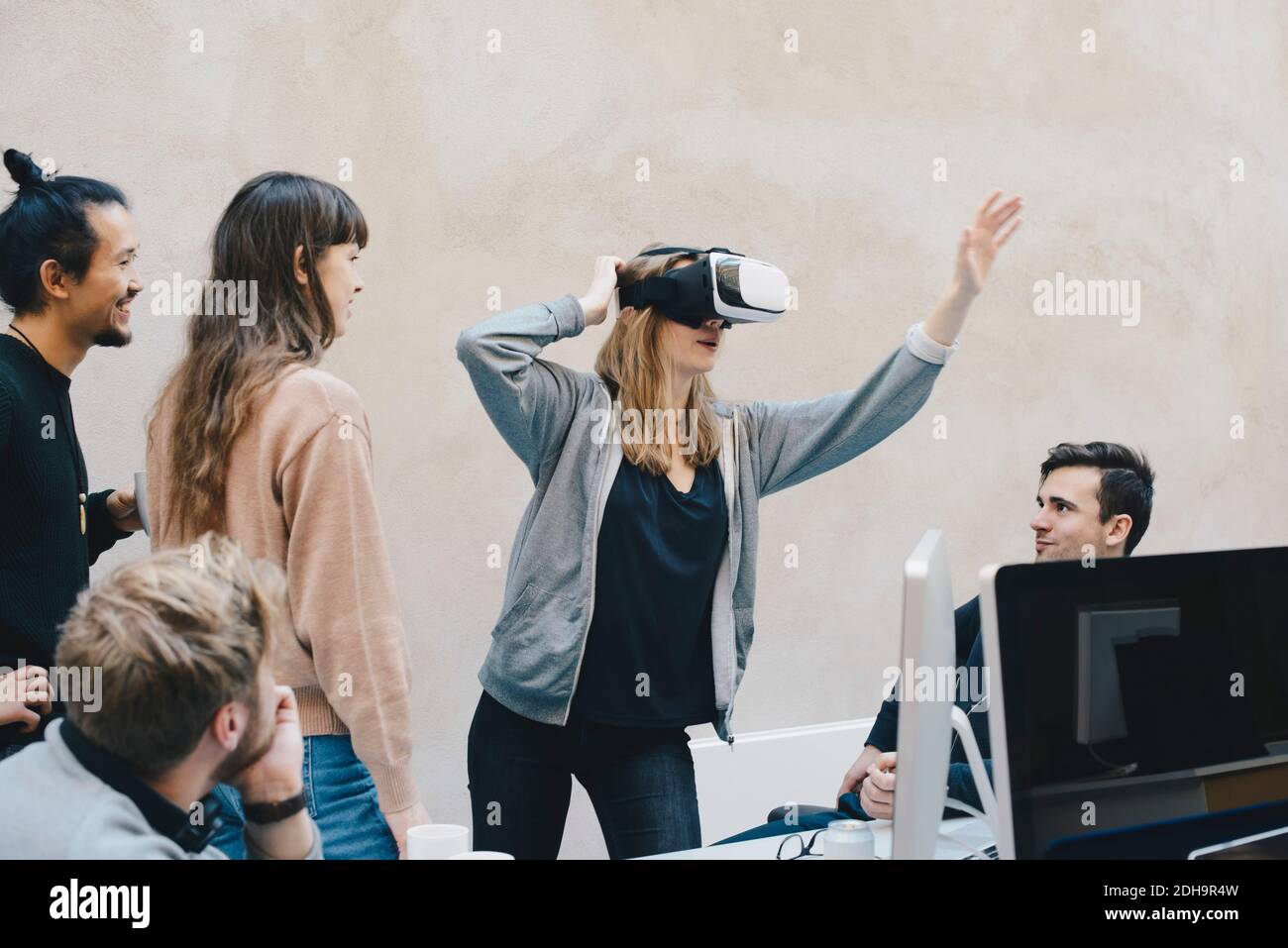 Female computer programmer using VR glasses while standing with colleagues in office Stock Photo