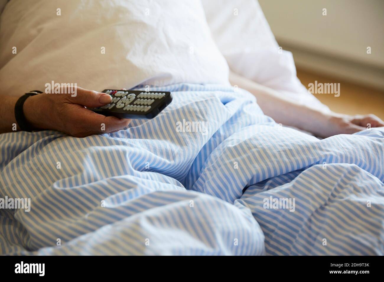 Midsection of senior man using remote control on hospital bed Stock Photo