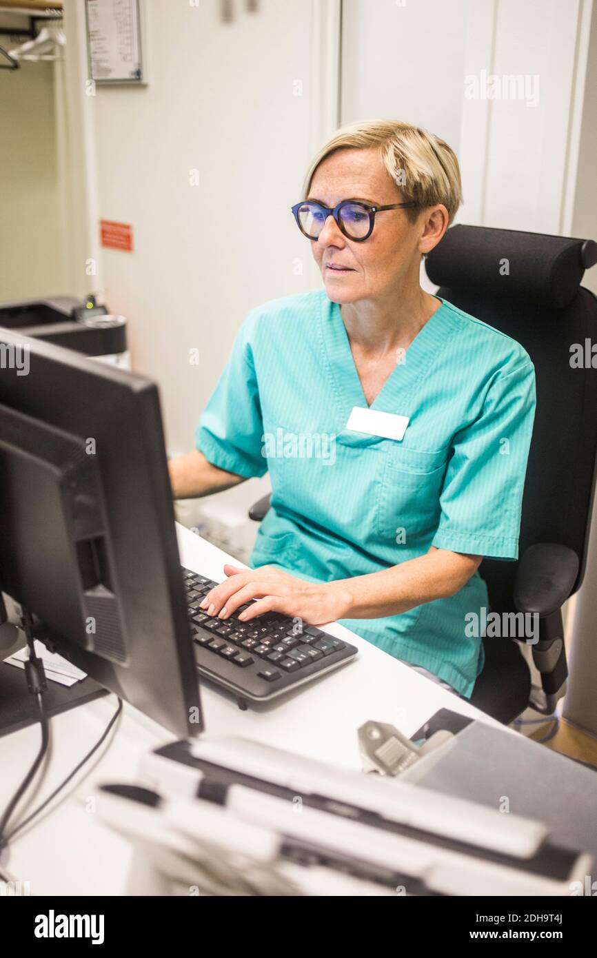 Female pediatrician working on computer while sitting in hospital Stock Photo