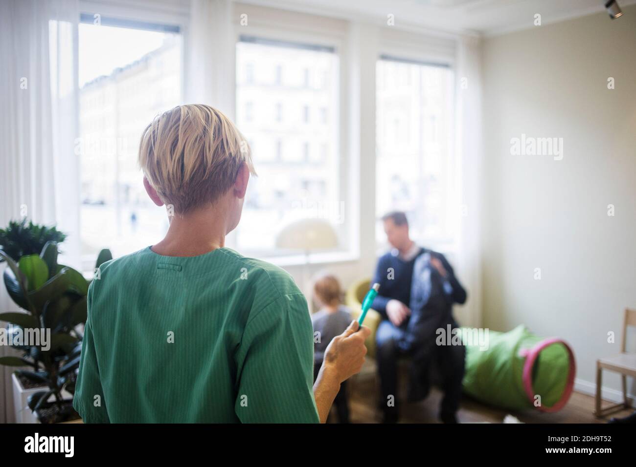 Rear view of pediatrician with pen standing in hospital Stock Photo