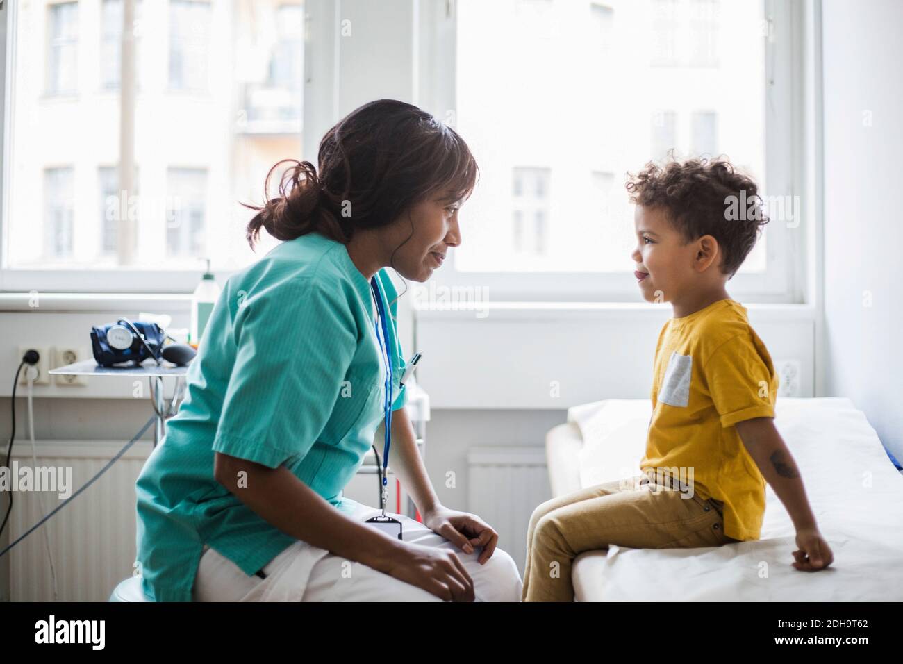 Female pediatrician looking at mischief boy in clinic Stock Photo