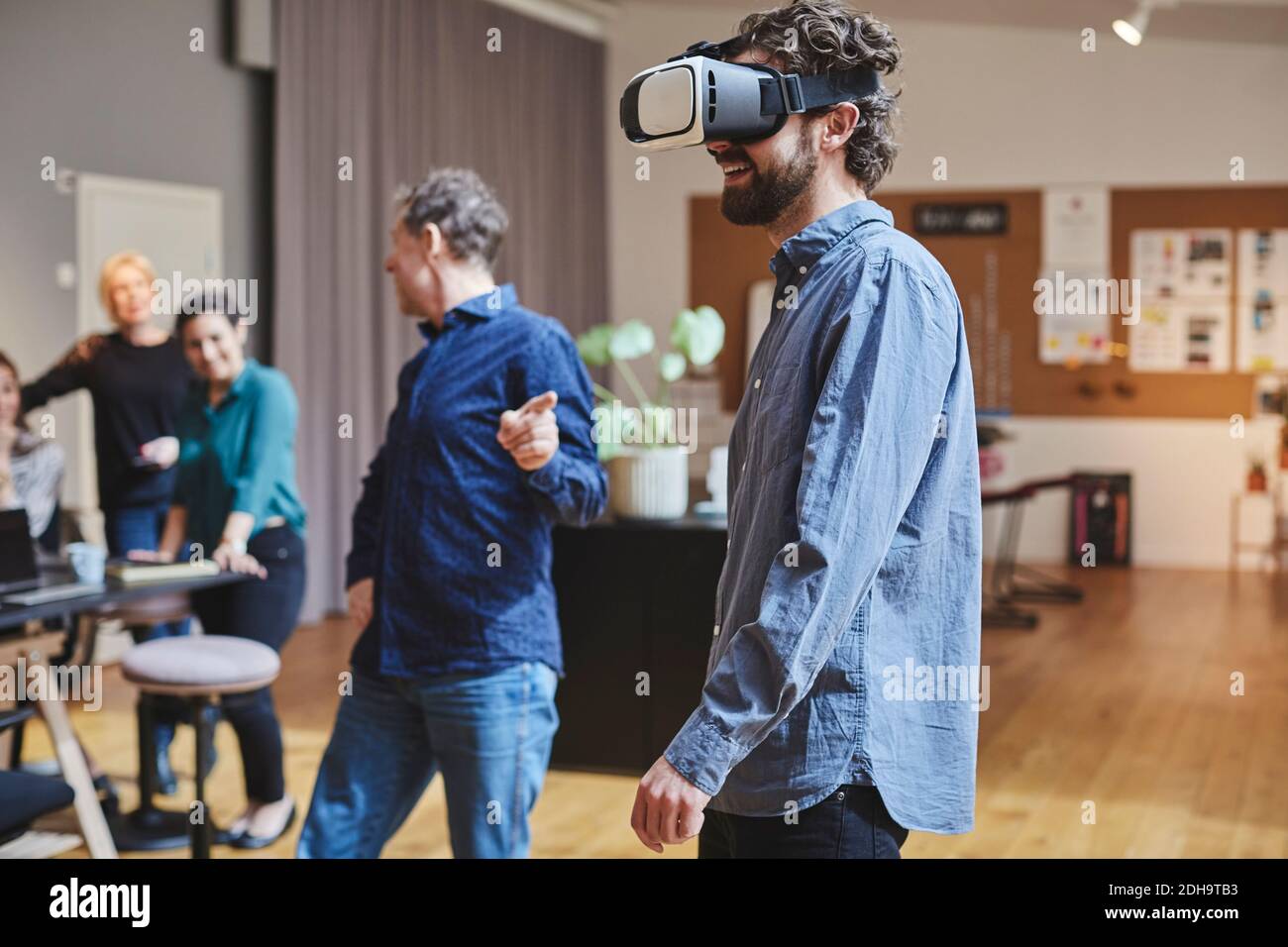 Businessman using virtual reality simulator while standing by colleagues in creative office Stock Photo