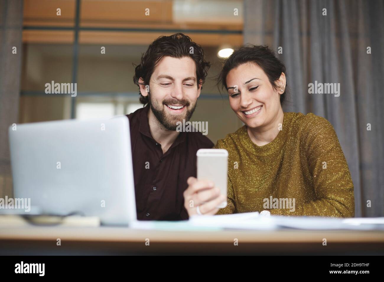 Smiling business colleagues using mobile phone at creative office Stock Photo