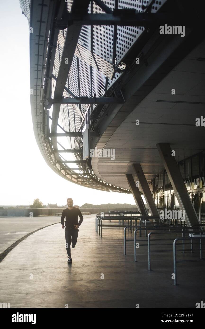 Young man running by built structure against sky Stock Photo