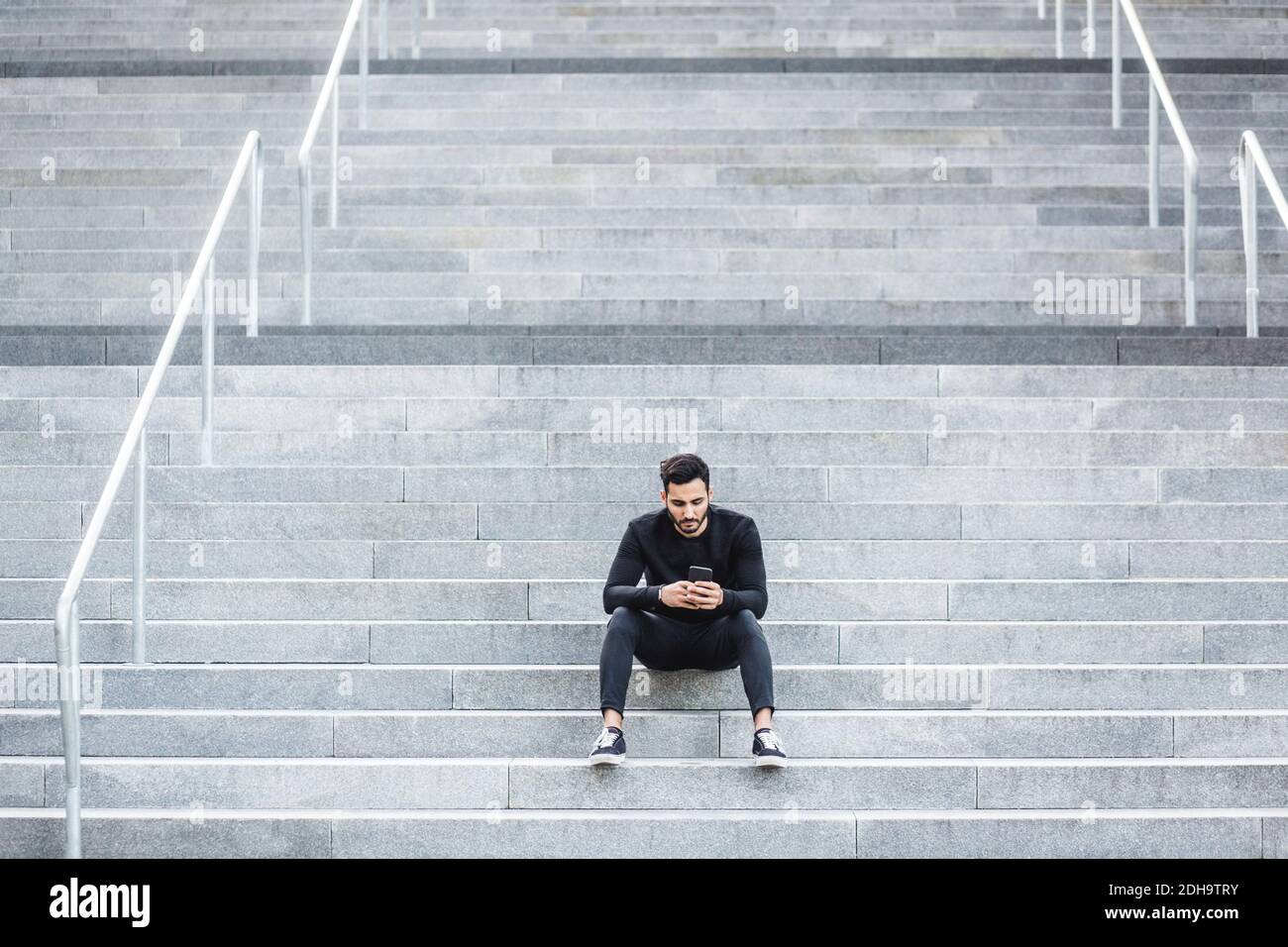 Young man using smart phone while sitting on staircase Stock Photo