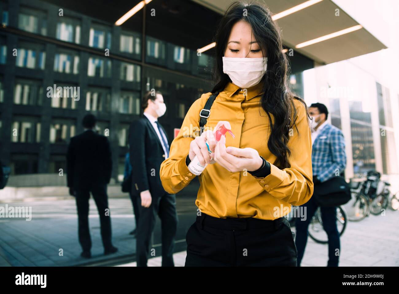 Woman with face mask using hand sanitizer Stock Photo