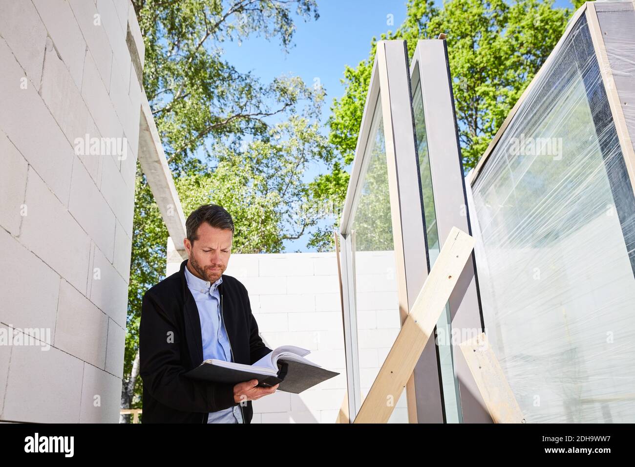 Low angle view of architect reading document while standing at construction site Stock Photo