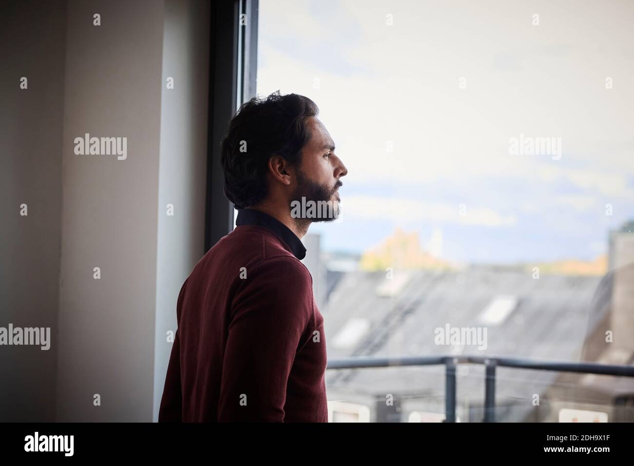 Contemplating businessman looking through window while standing in office Stock Photo