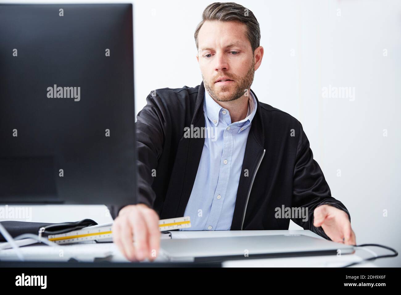 Serious architect using computer at desk in creative office Stock Photo