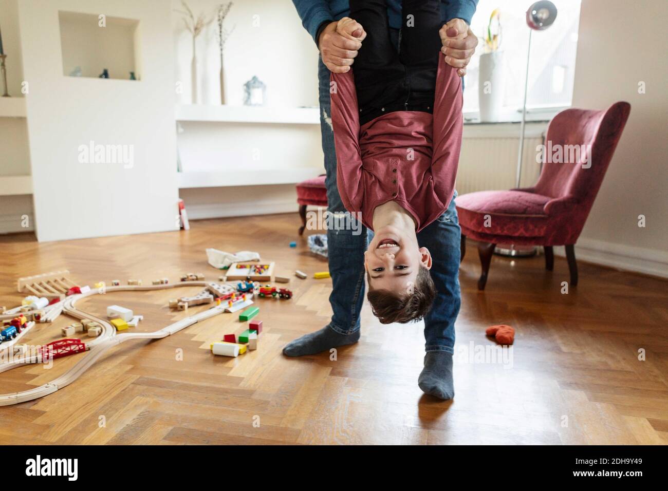 Low section of father lifting son in living room Stock Photo