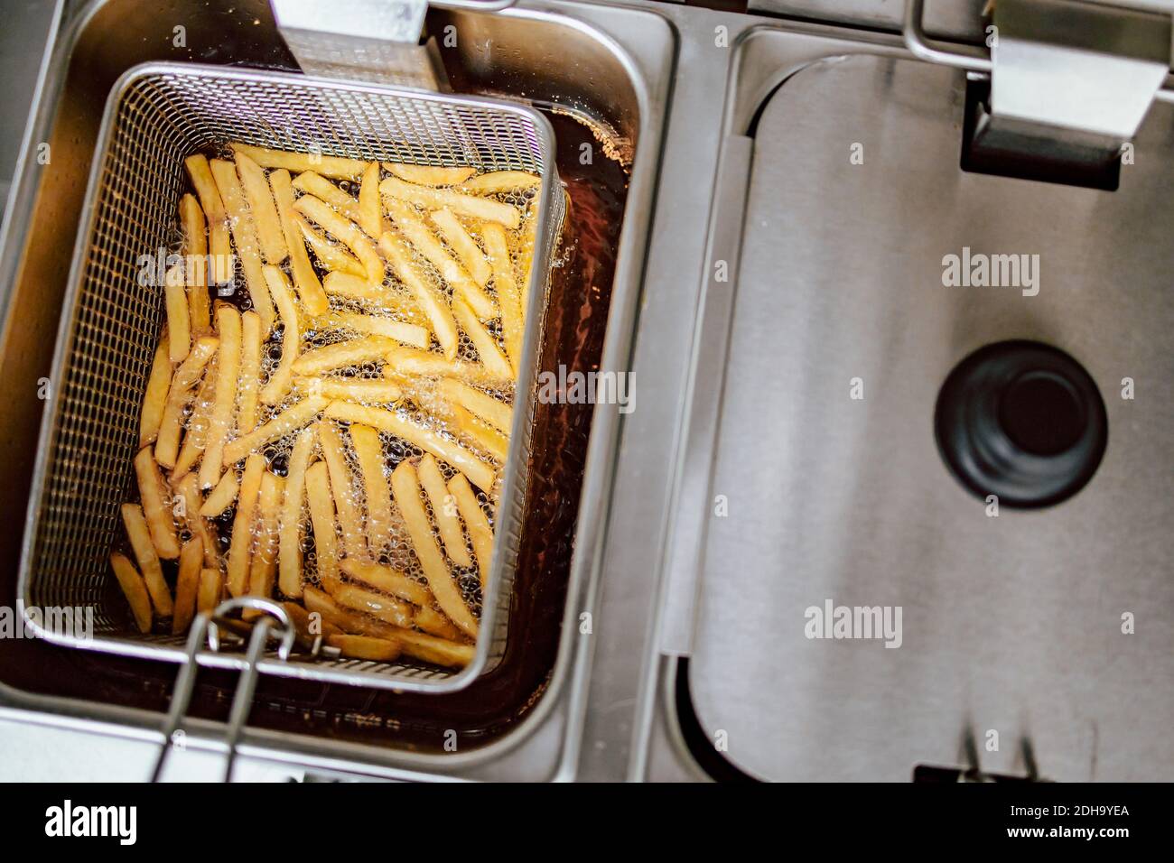 Top view of fries in deep fryer. Restaurant meal preparation, side dish