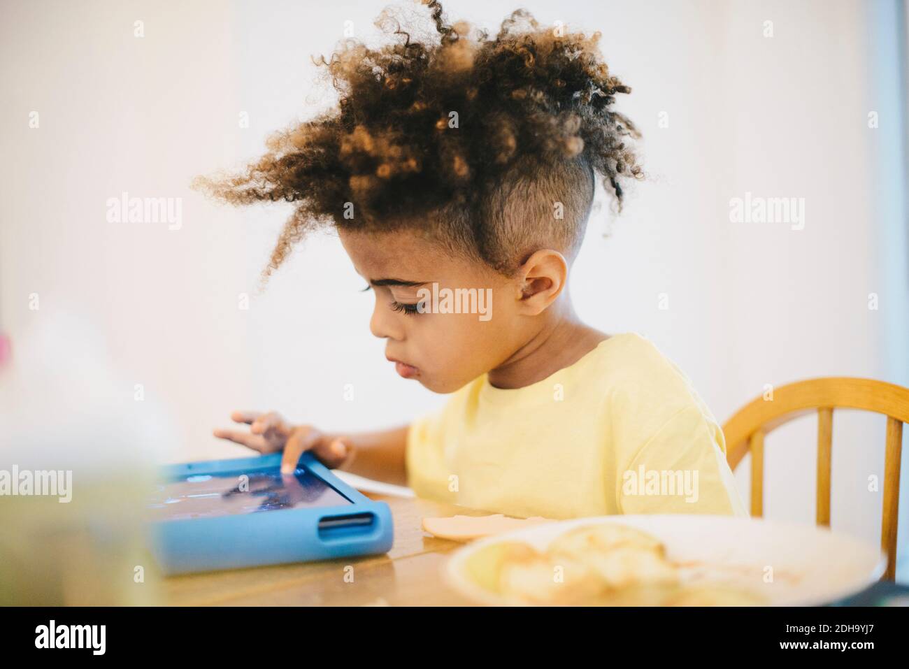 Close-up of boy using digital tablet while sitting at table Stock Photo