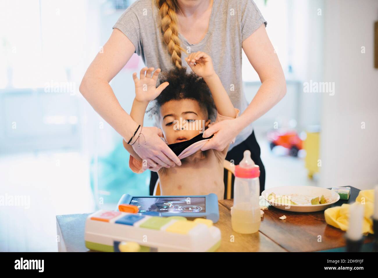 Midsection of mother dressing son at table Stock Photo