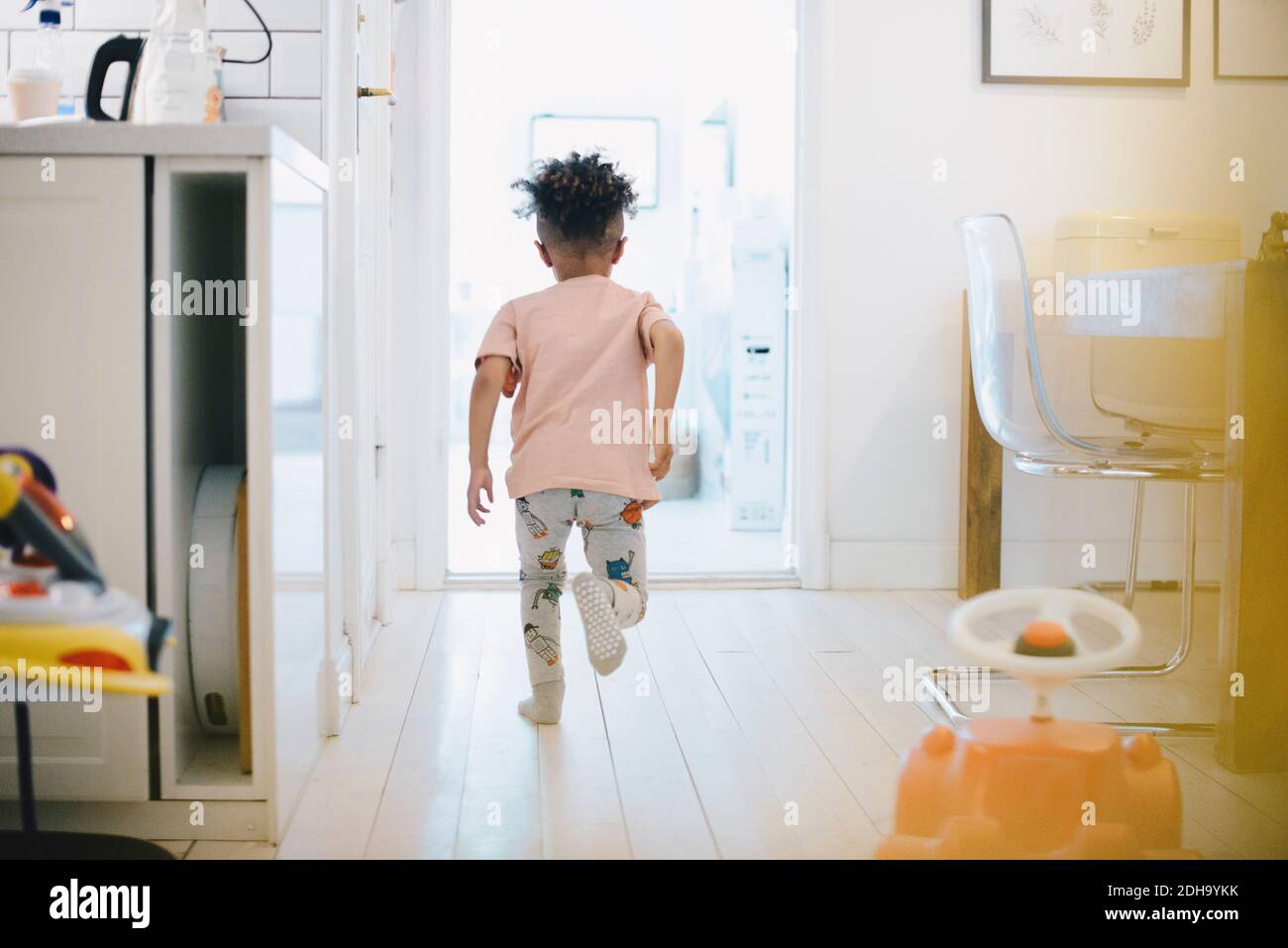 Rear view of boy running towards doorway at home Stock Photo