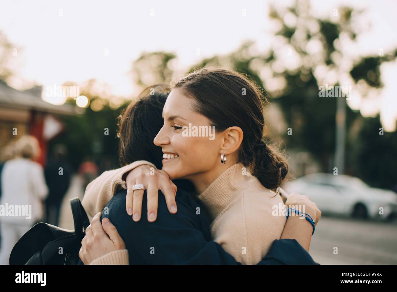 Smiling young woman embracing female friend in city Stock Photo