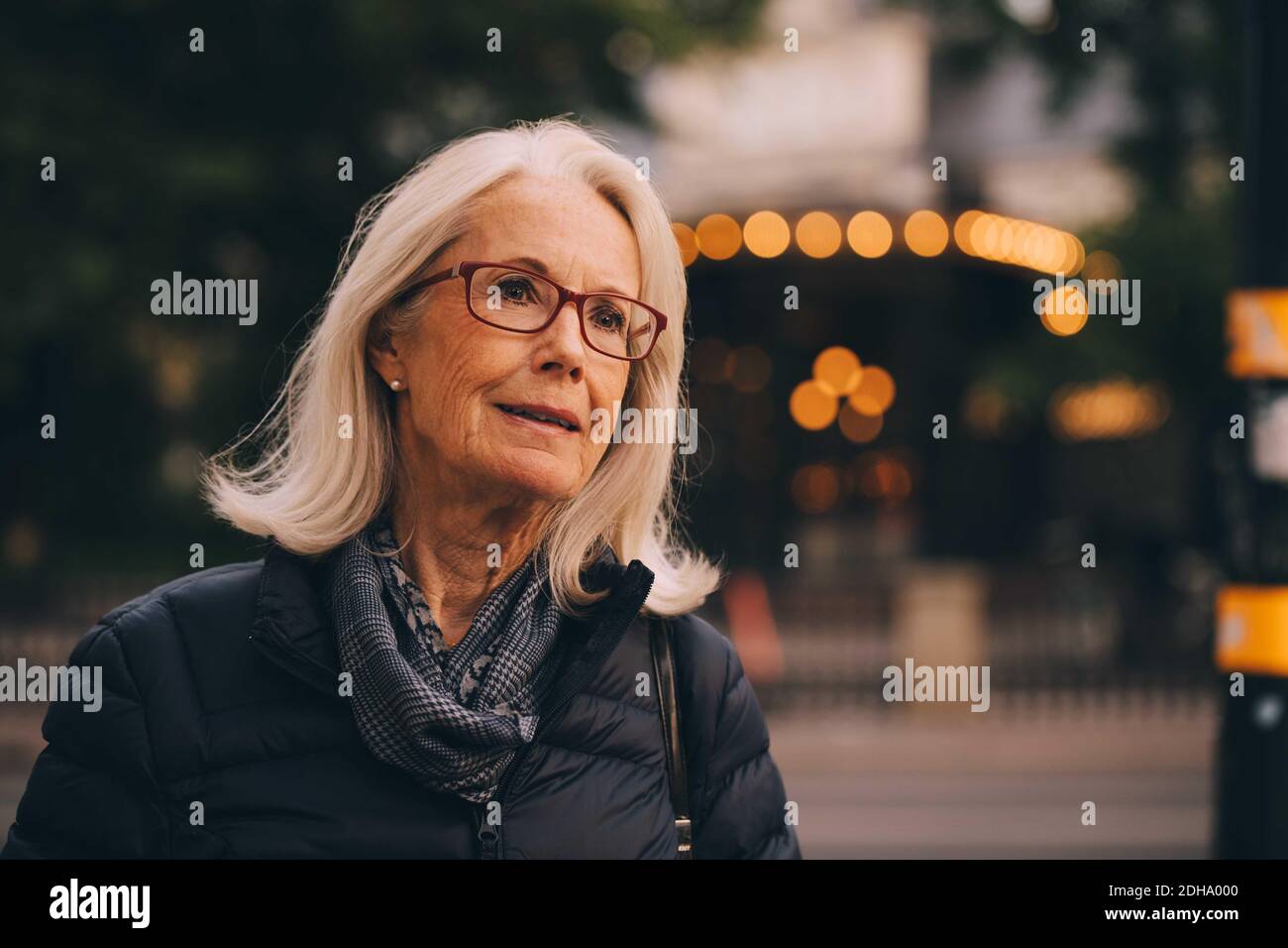 Senior woman looking away while standing in city Stock Photo