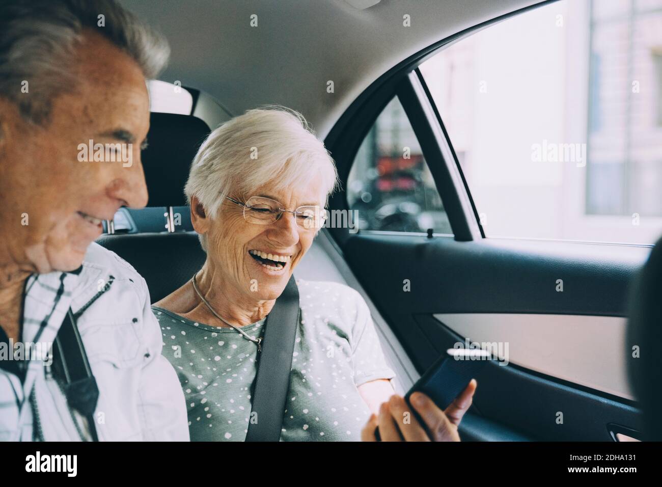 Smiling retired couple using mobile phone while sitting in car during vacation Stock Photo