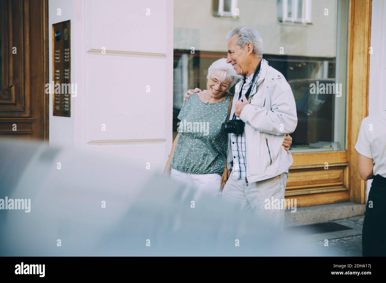 Happy elderly couple with arm around walking on sidewalk in city Stock Photo