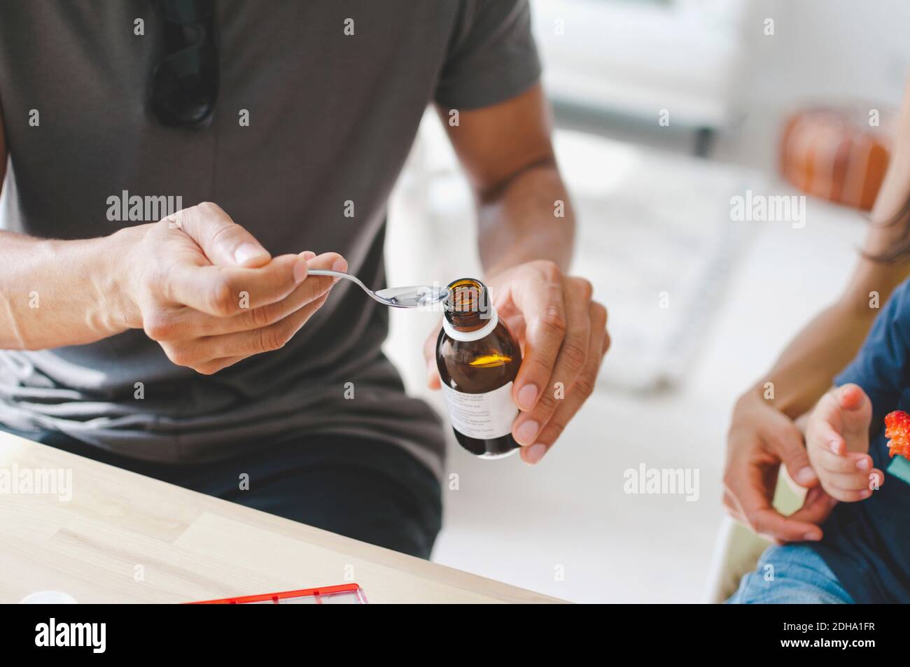 Father giving medicine to son sitting with mother at home Stock Photo