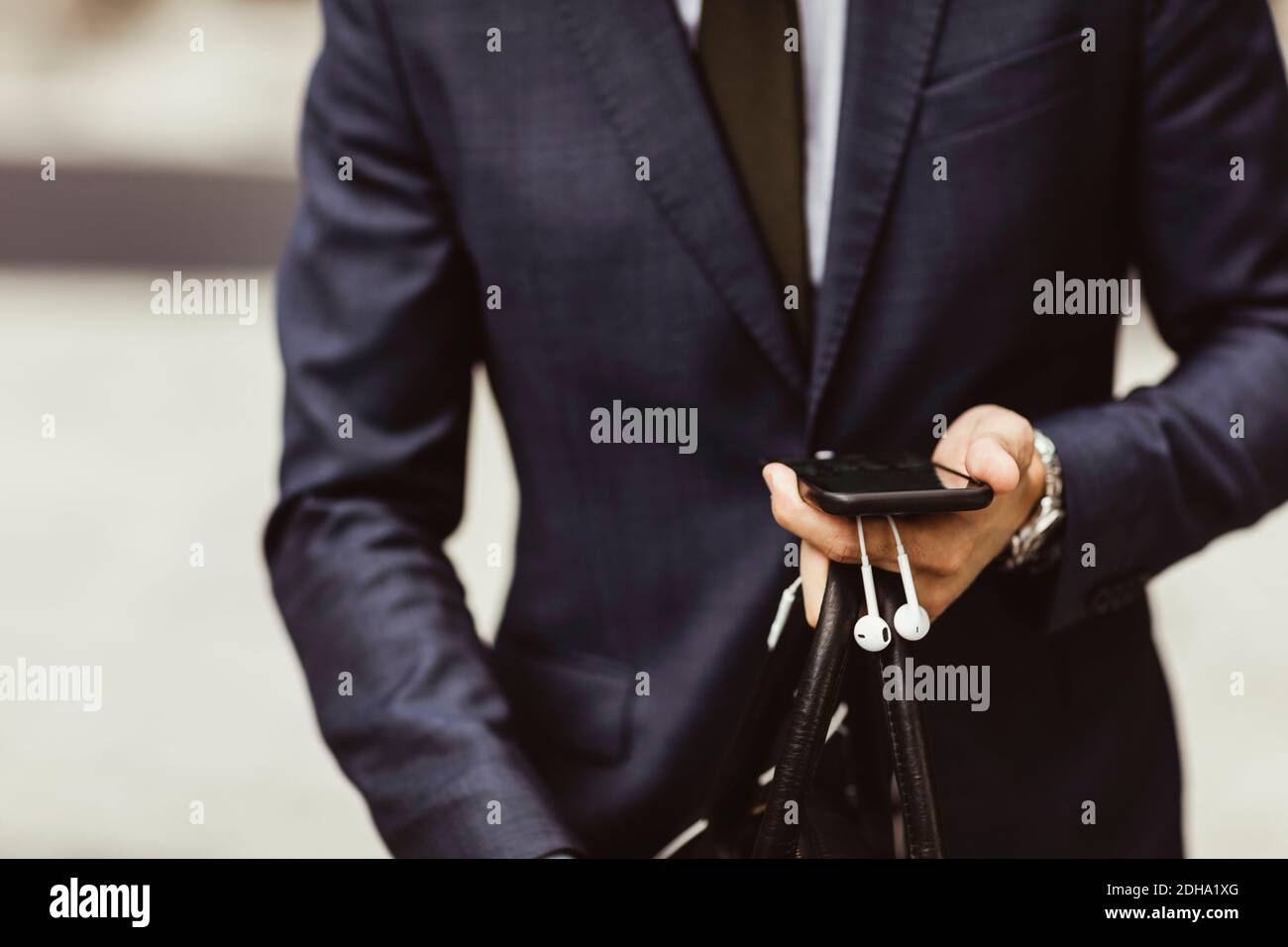 Midsection of male entrepreneur using smart phone while standing outdoors Stock Photo