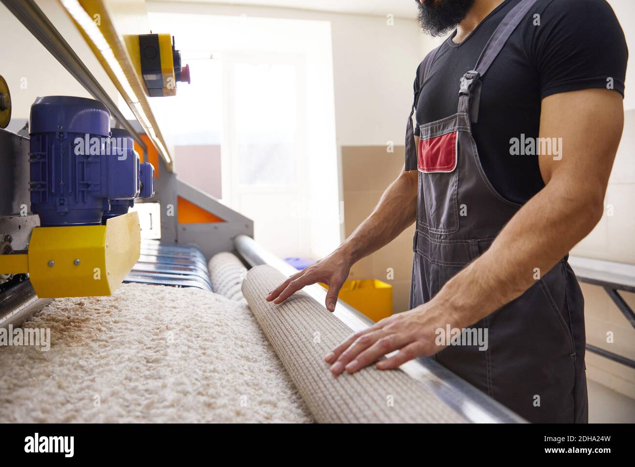 Man operating carpet automatic washing machine in professional laundry service Stock Photo