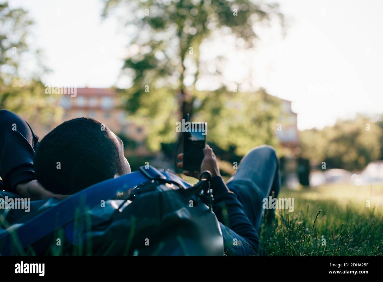 Young man using mobile phone while lying on grass Stock Photo