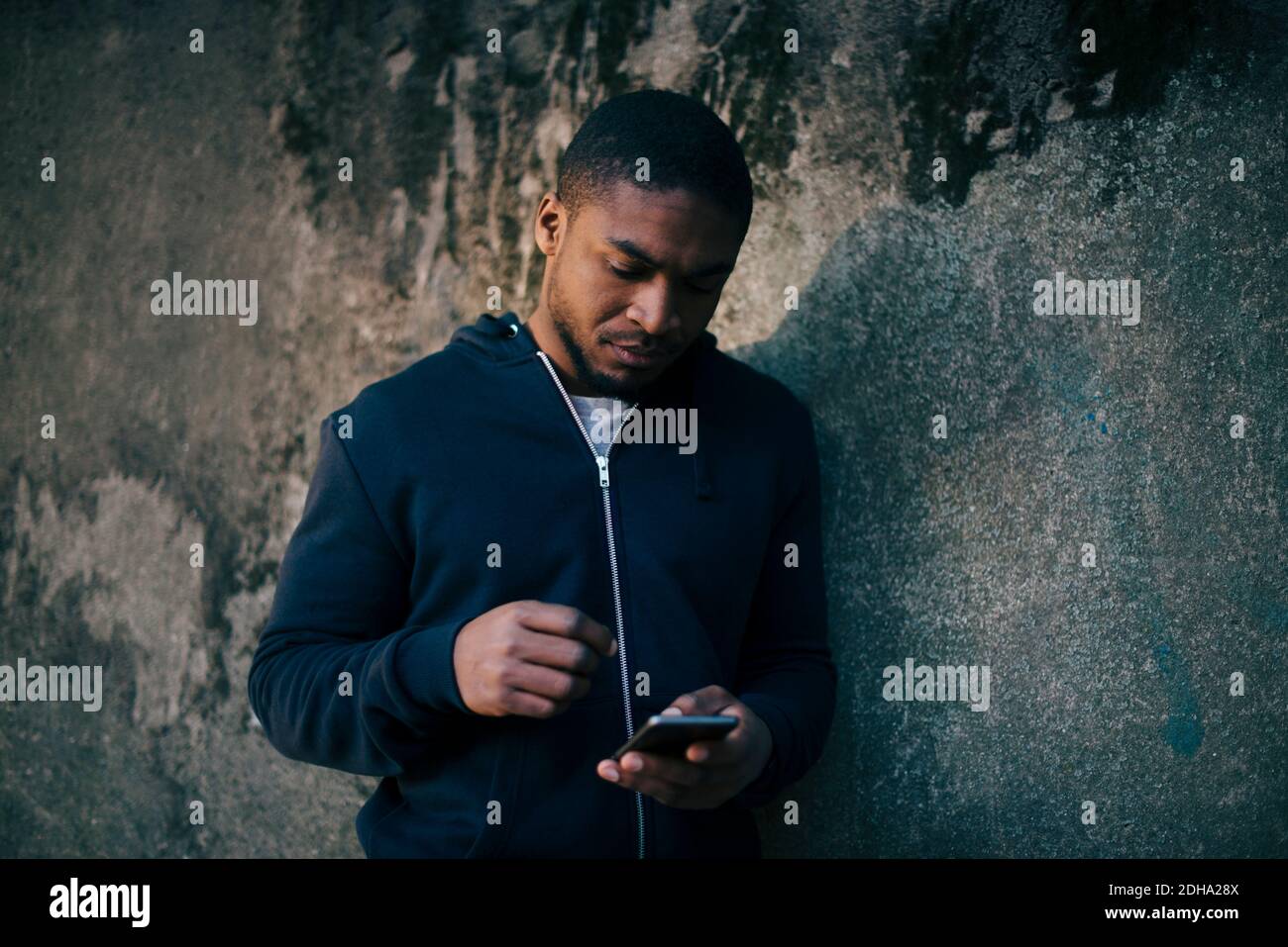 Young man leaning on wall while using smart phone Stock Photo