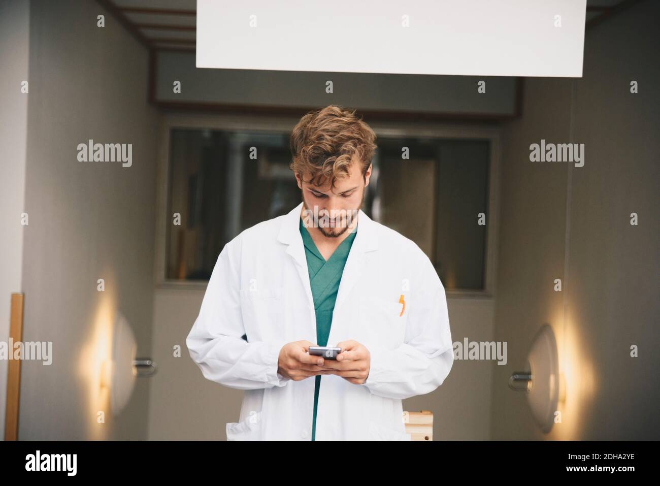 Young male doctor using mobile phone at hospital Stock Photo