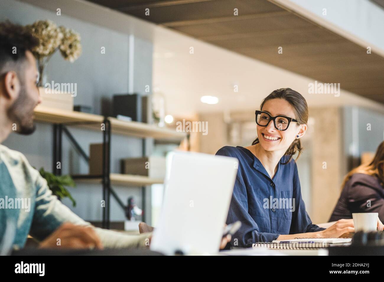 Smiling businesswoman looking at coworker while working in creative office Stock Photo